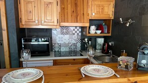 Une cuisine avec des meubles en bois, un four à micro-ondes, une machine à café et un verre à vin posé sur le comptoir.
