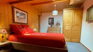 Une chambre à coucher avec un lit en bois, une table de chevet, une lampe, une commode et une armoire.