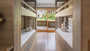 A corridor with bunk beds, wooden walls, and a view of a garden through a glass door. - Luxury Apartment, 3 Bedrooms, Close to Slopes, Sauna (Méribel)