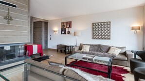 A modern living room with a glass coffee table, a sofa, a red rug, and a fireplace. - Luxury Apartment, 3 Bedrooms, Close to Slopes, Sauna (Méribel)