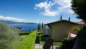 Una casa con vista al mar, un jardín y un banco de madera.