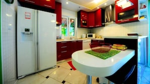 A modern kitchen with red cabinets, a white refrigerator, and a microwave. - 4 Bed Villa Sleeps 9 - Pool, Pets, Garden, Parking (Supetar)