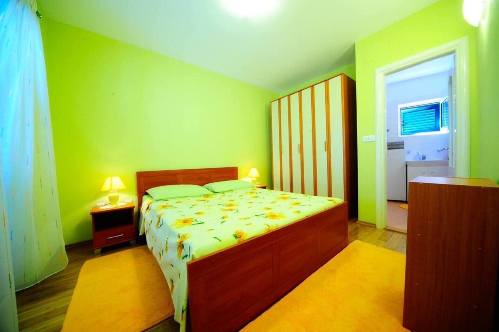 A bedroom with a bed, nightstands, a wardrobe, and a desk.