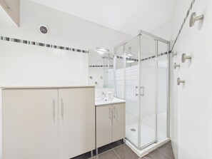 A modern bathroom with a glass shower enclosure, white tiled walls, and a beige vanity with a mirror. - Central Les Gets Apartment with Terrace, Garage and WIFI (Les Gets)