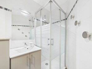 A modern bathroom with a glass shower enclosure, a white sink, and a mirror. - Central Les Gets Apartment with Terrace, Garage and WIFI (Les Gets)