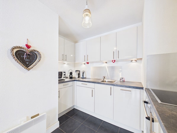 A modern kitchen with white cabinets, a stainless steel sink, and a light fixture.