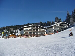 A ski resort with multiple buildings, including a restaurant and a hotel with balconies.