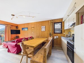 Een houten interieur met een eethoek, keuken en een aan de muur bevestigde televisie.
