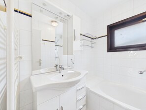 Een moderne badkamer met een wit wastafelmeubel, spiegel en bad.