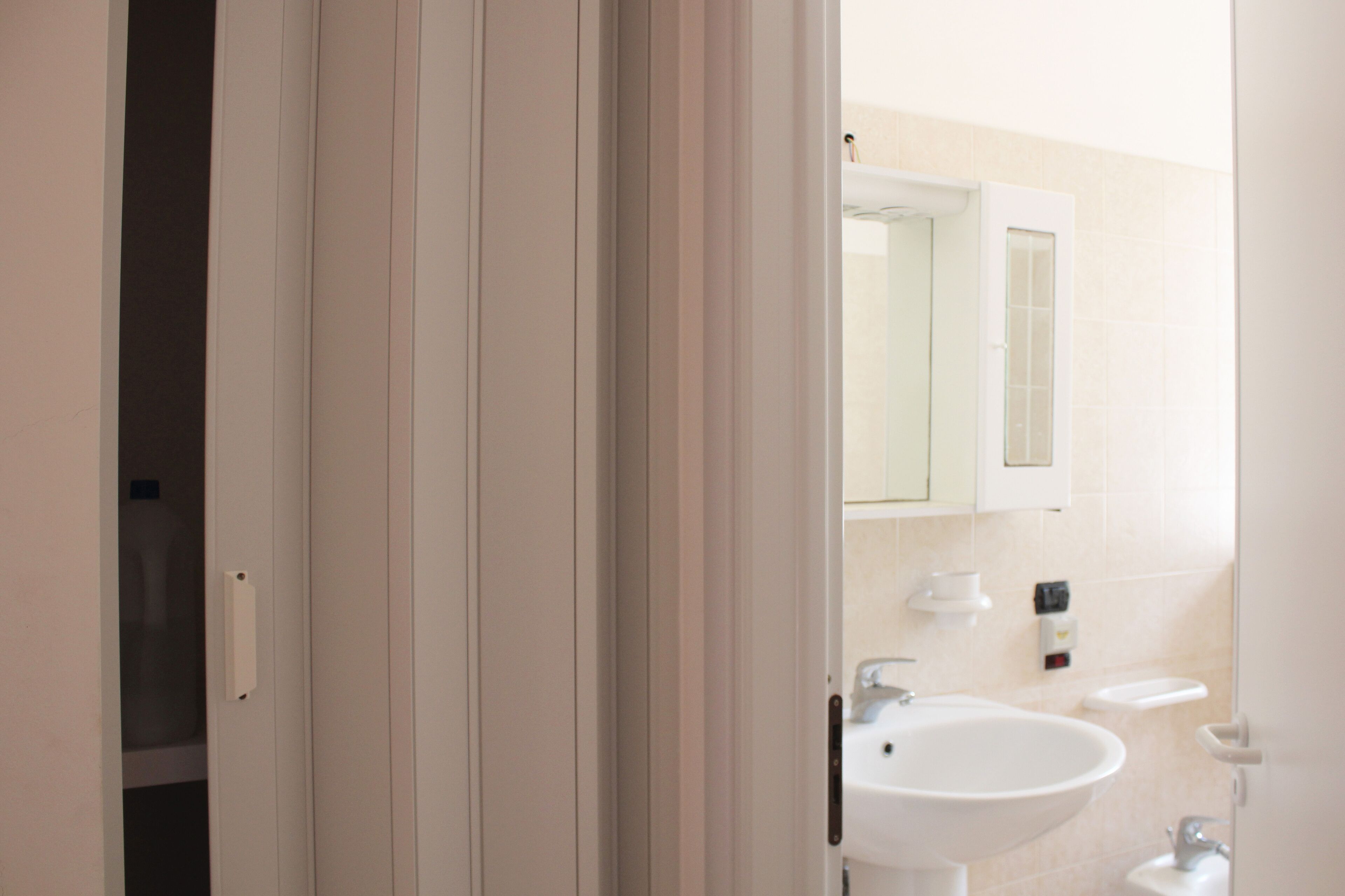 Une salle de bain avec un lavabo blanc, un miroir et un meuble.