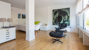 Ein modernes Schlafzimmer mit einem Bett, einem Schreibtisch, einem Sessel und einem großen Gemälde.
