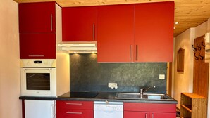 A compact kitchen with red cabinets, a white dishwasher, and a Bosch oven.