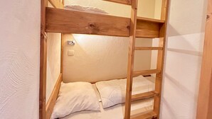 A bunk bed with a wooden frame and white bedding.