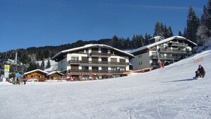 A ski resort with multiple buildings, including a restaurant and a hotel with balconies. - Ski-in/Ski-out Apartment with Terrace & Summer BBQ, Near Village Center (Les Gets)