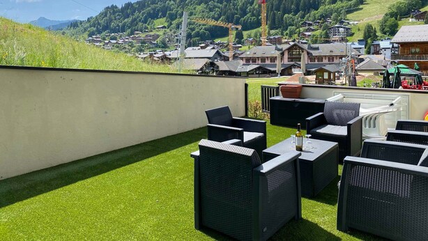 A terrace with outdoor furniture and a view of a village and mountains. - Ski-in/Ski-out Apartment with Terrace & Summer BBQ, Near Village Center (Les Gets)