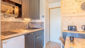 Una cocina moderna con armarios oscuros, un lavamanos de acero inoxidable y una encimera de madera.