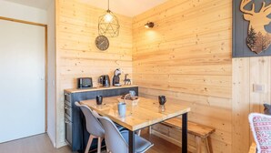 Un interior de madera cálido con una mesa de comedor, sillas, una máquina de café y un reloj en la pared.