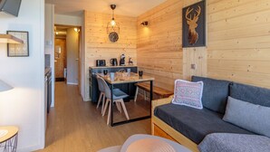 Una habitación acogedora con una pared de madera, un sofá, una mesa de comedor con sillas y un televisor colgado en la pared.