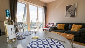 Un coin repas avec une table dressée pour deux personnes, une bouteille de vin et des verres à vin.