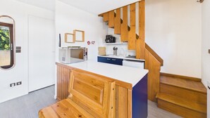 A compact kitchen with a built-in microwave, a sink, and a wooden staircase. - Spacious apartment in the center, 6 guests (Les Gets)