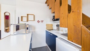 A compact kitchen with a microwave, sink, and wooden cabinets. - Spacious apartment in the center, 6 guests (Les Gets)
