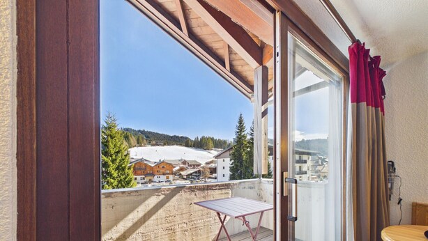 A balcony with a view of a snowy mountain and buildings. - Spacious apartment in the center, 6 guests (Les Gets)