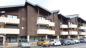 A multi-story building with a modern architectural design, featuring balconies and large windows. - Spacious apartment in the center, 6 guests (Les Gets)