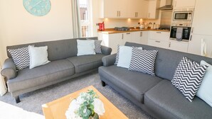 A living room with two grey sofas, a wooden coffee table, and a wall clock. - Eden Lodge - Sherwood 21 (Carnforth)