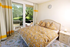 Een slaapkamer met een bed, nachtkastje, klok en uitzicht op het omliggende landschap.