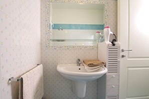 Een badkamer met een wit wastafel, een spiegel en een handdoekrek.