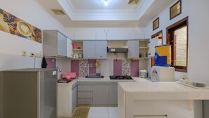 A compact kitchen with white cabinets, a gas stove, and a sink. - Homestay Jogja Dekat Masjid Jogokaryan by Simply Homy (Yogyakarta)