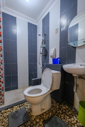 A bathroom with a toilet, shower, sink, and tiled walls. - Homestay Jogja Dekat Masjid Jogokaryan by Simply Homy (Yogyakarta)