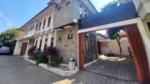A two-story house with a balcony, a covered entrance, and a paved driveway. - Homestay Jogja Dekat Masjid Jogokaryan by Simply Homy (Yogyakarta)