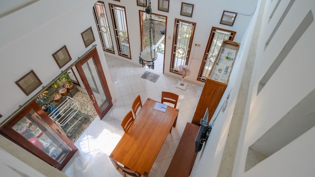 A dining area with a wooden table and chairs, a bench, and a refrigerator. - Homestay Jogja Dekat Masjid Jogokaryan by Simply Homy (Yogyakarta)