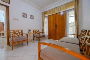 A hotel room with a bed, two wooden chairs, a small table, and a wardrobe. - Homestay Jogja Dekat Masjid Jogokaryan by Simply Homy (Yogyakarta)