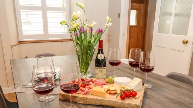 Une table à manger avec une planche à fromage, des verres à vin et une bouteille de vin.