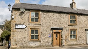 Un bâtiment en pierre avec une enseigne indiquant « The Gables » et une épicerie de village.
