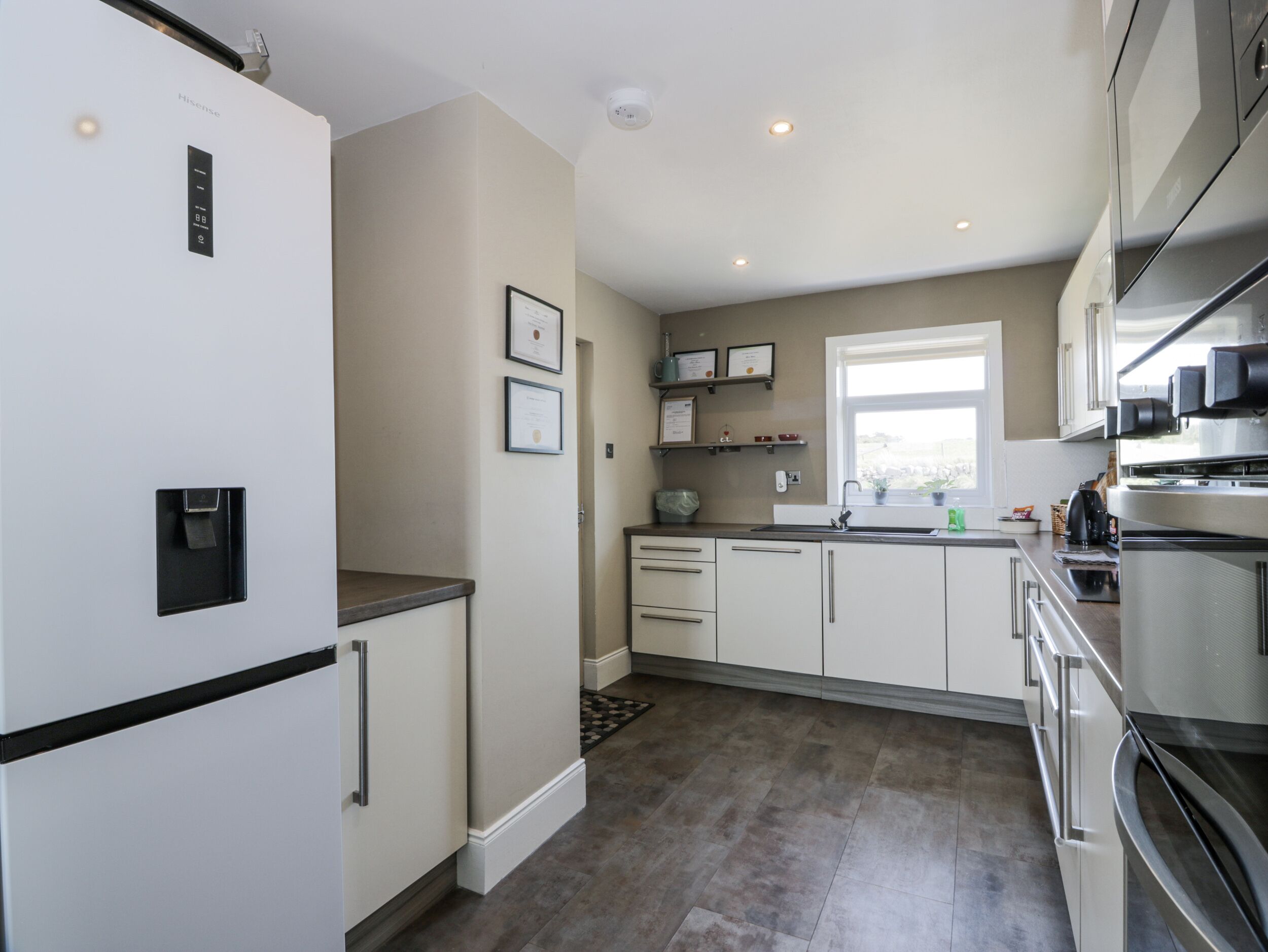 A modern kitchen with white cabinets, stainless steel appliances, and a window providing natural light.