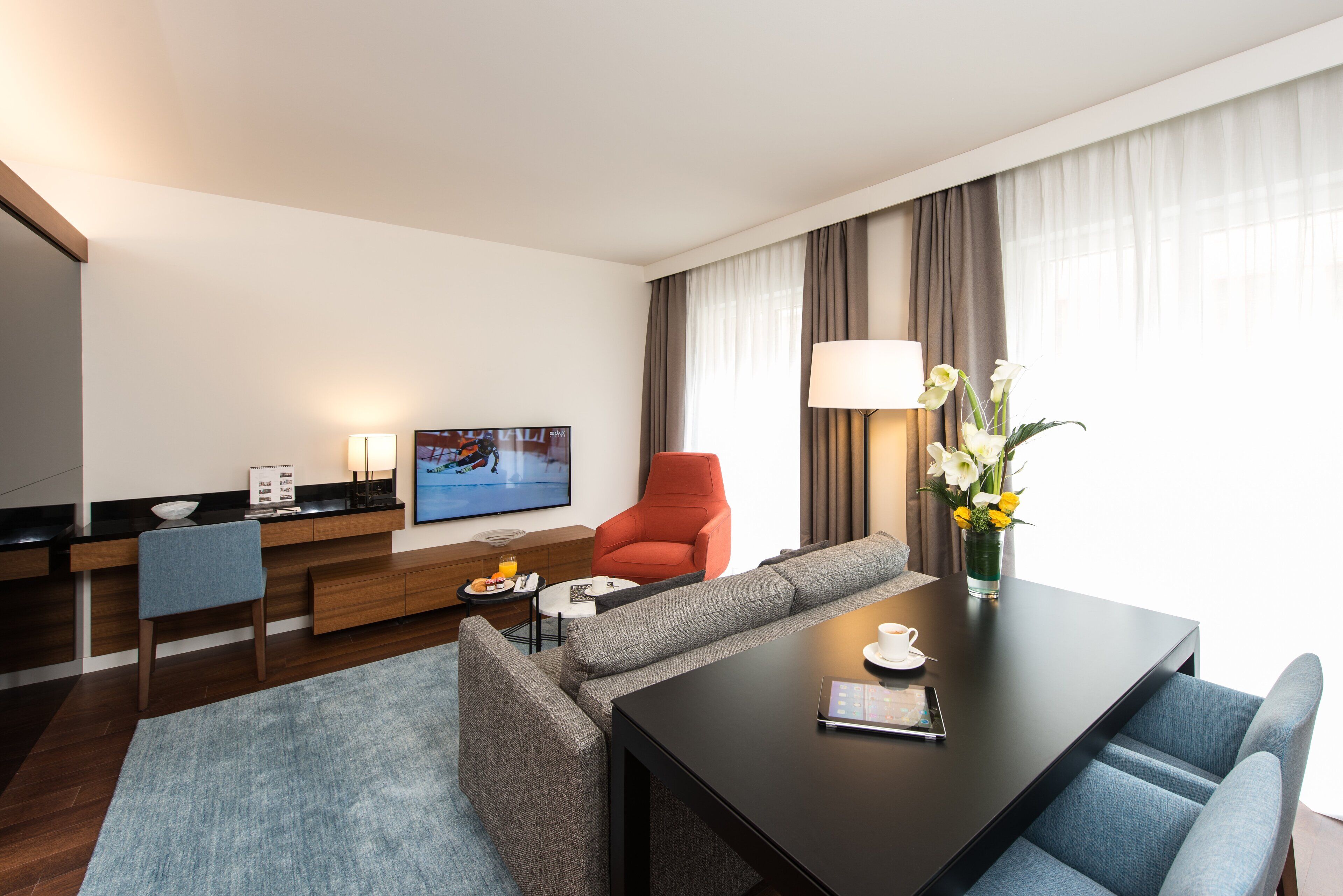 Une chambre d’hôtel moderne équipée d’un canapé, d’une table à manger, d’un téléviseur et d’une lampe.