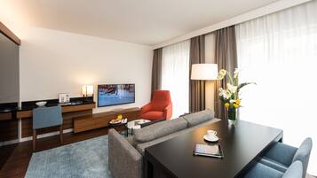 Une chambre d’hôtel moderne équipée d’un canapé, d’une table à manger, d’un téléviseur et d’une lampe.