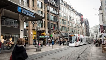 A tram passing by a commercial area with shops and a bank.