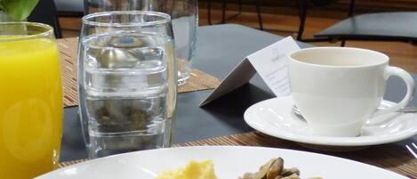 A breakfast setting with a plate of food, glasses of water and orange juice, and a cup on a table.