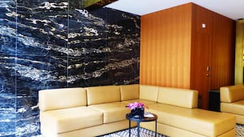 Una sala de estar moderna con un sofá color beige, una mesita redonda con un florero y una alfombra estampada.