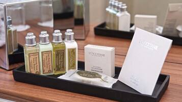 A display of L'OCCITANE shower cap and toiletries on a wooden tray.