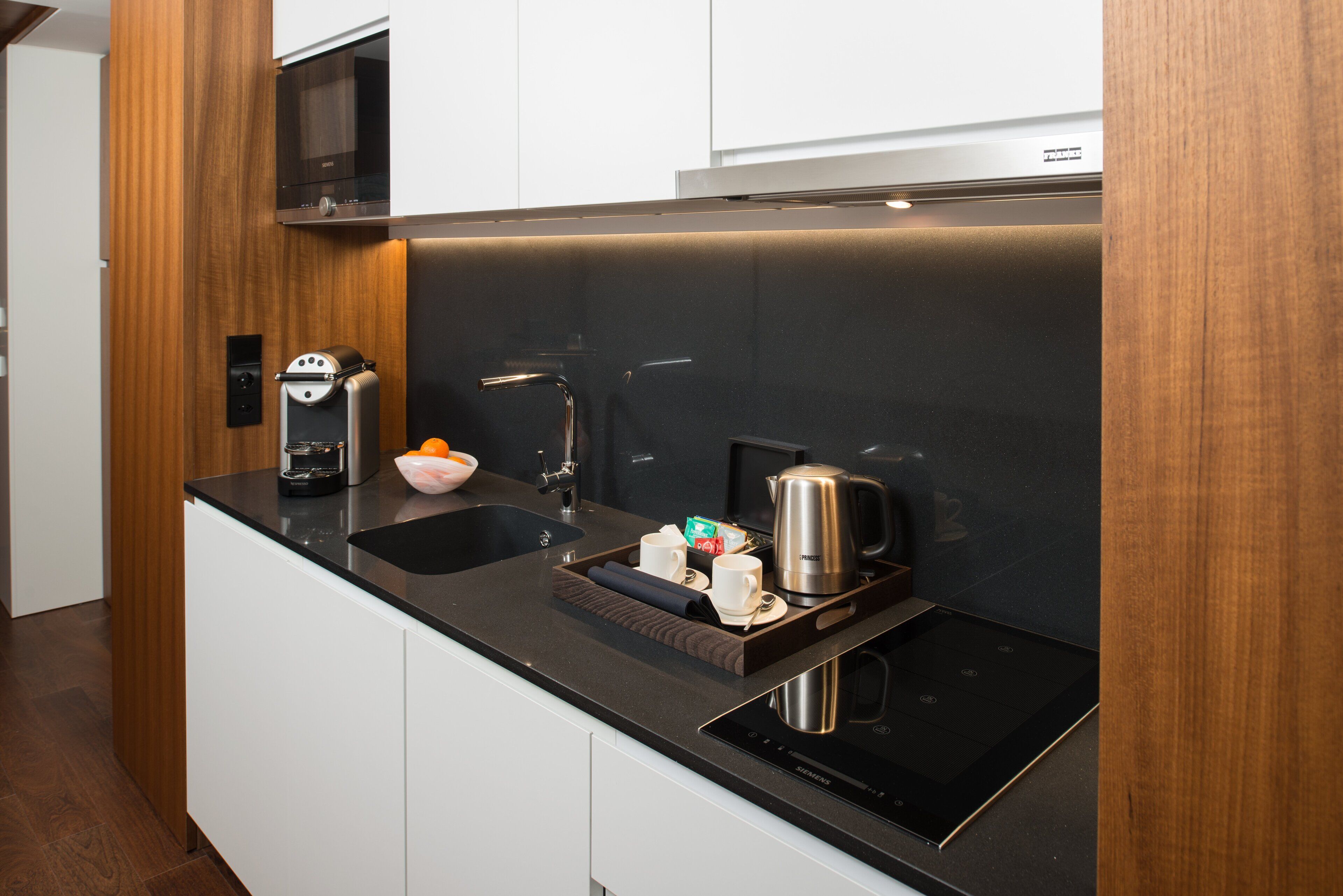 A modern kitchen with a black countertop, stainless steel appliances, and wooden cabinetry.