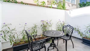 A small patio with a round table and two chairs, surrounded by potted plants and flowering plants. - Ni Hotel Lara (Antalya)