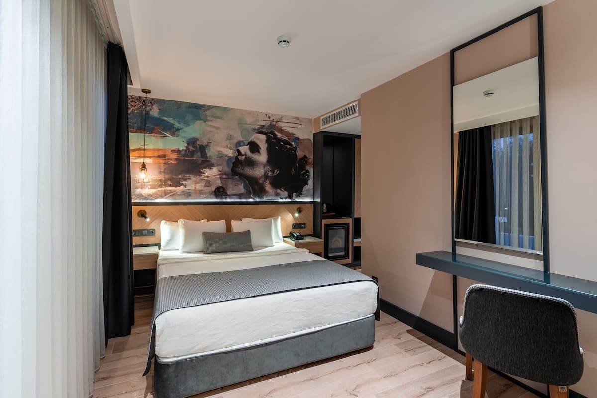 A modern hotel room with a large bed, a desk, and a large mirror.