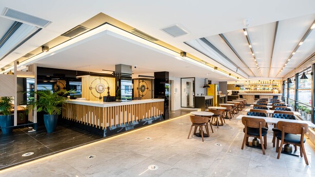 A modern restaurant with a central counter, seating area, and large windows. - Ni Hotel Lara (Antalya)