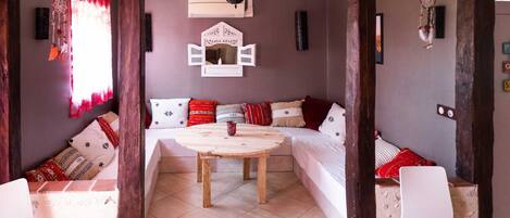 Una habitación acogedora con una mesa de madera, sofá blanco y un tapiz decorativo.
