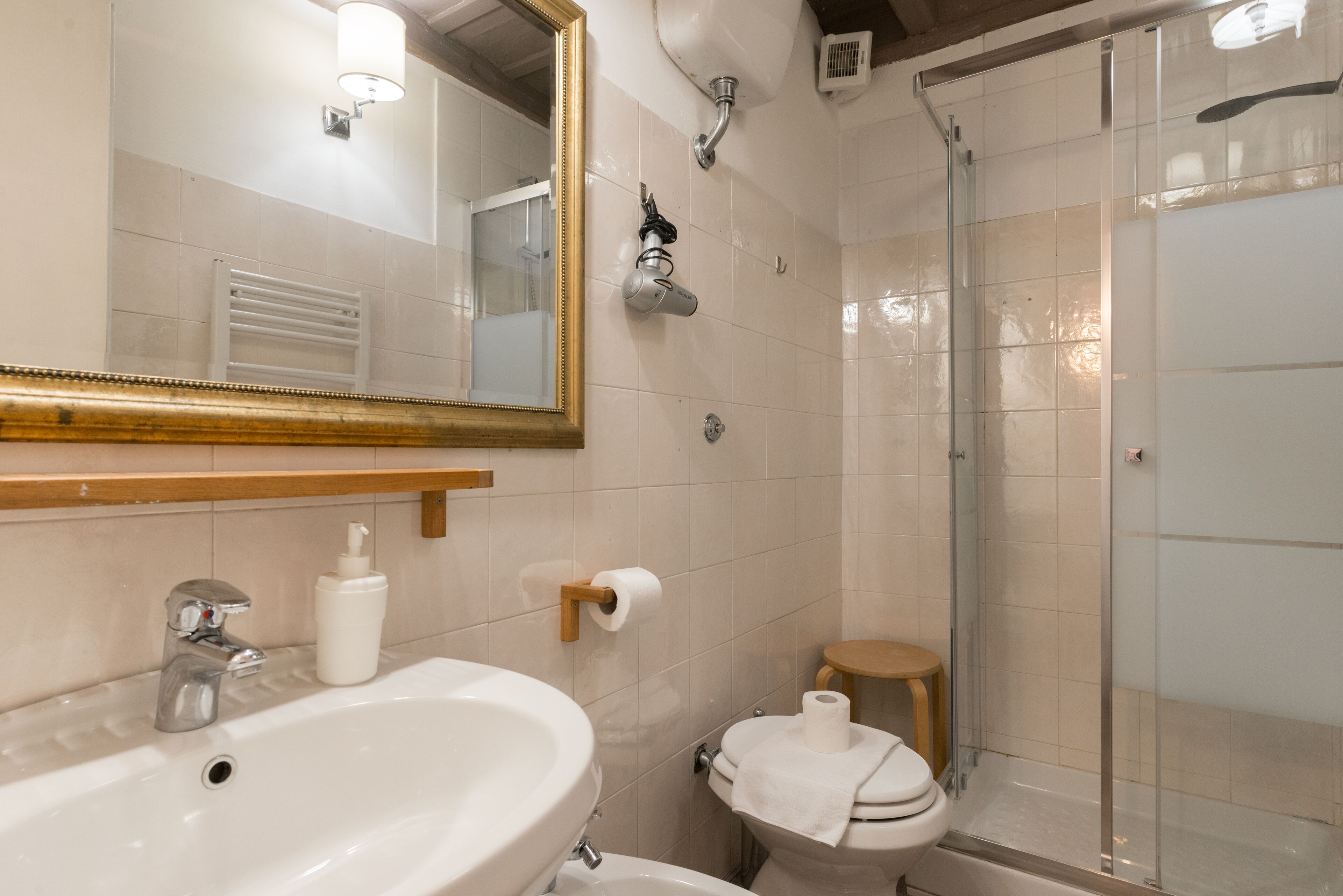 A bathroom with a sink, mirror, toilet, and shower.